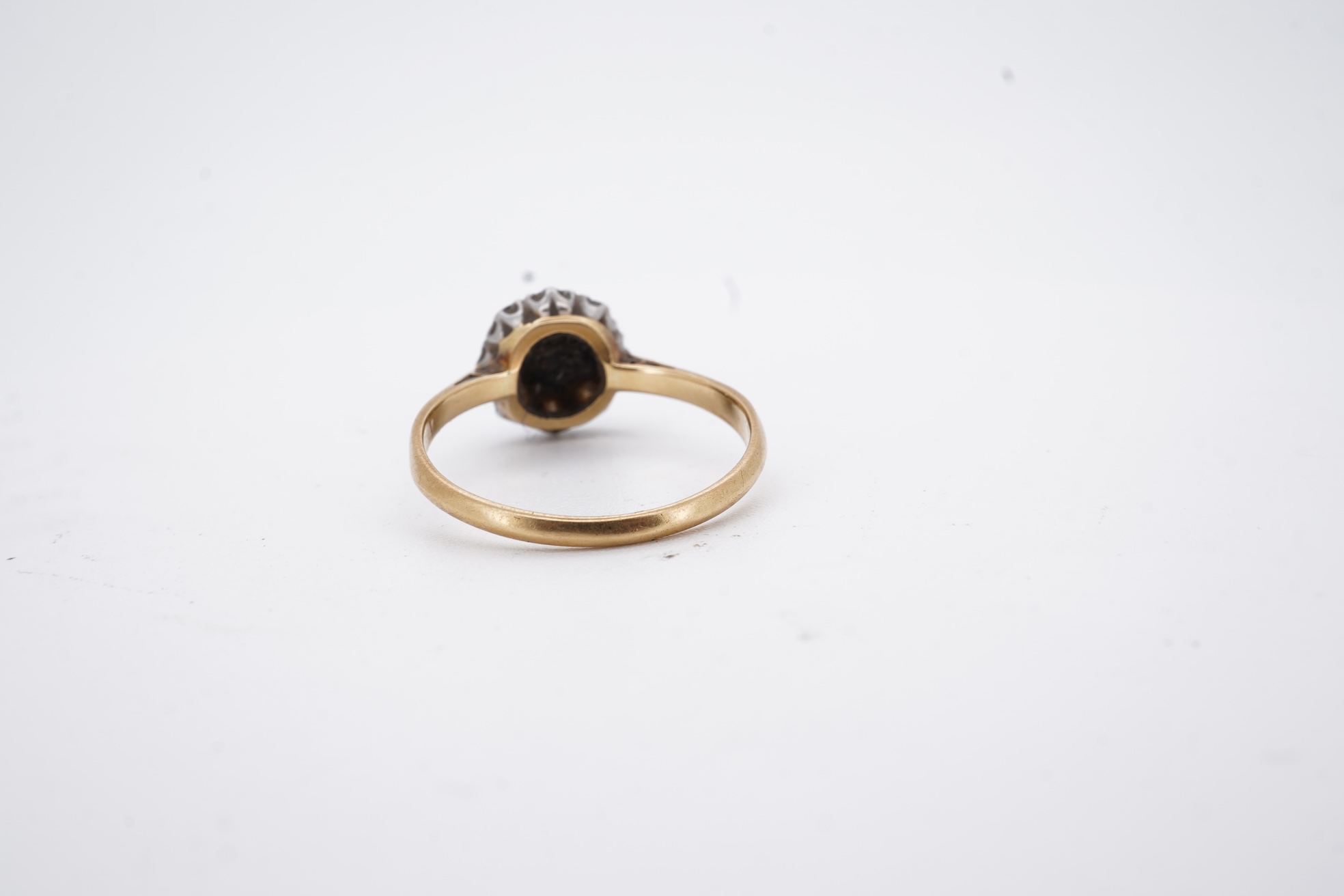 An early 20th century 18ct, plat. and nine stone diamond cluster ring, the central diamond weighing approximately 0.30ct, size Q, gross weight 3.1 grams.